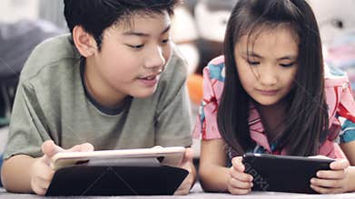 Asian boy and girl playing game on mobile phone together with smiling faces.