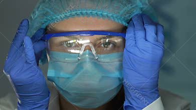 Female lab assistant wearing safety glasses before chemical research, close-up