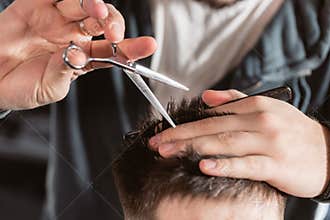 Close-up Hair cutting with metal scissors. Master cuts hair and beard of men in the barbershop, hairdresser makes