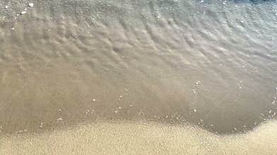 Closeup Of Sea Waves Washing Ashore A Sandy Beach