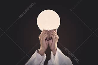 Priest hands lifting a communion bread