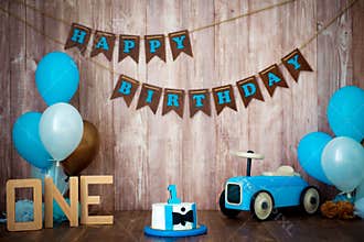 Photoshoot crush smashcake for a little boy gentleman. Decorated photozone with a wooden retro car and helium balloons. Happy