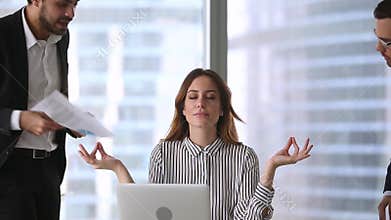 Calm businesswoman taking break meditating at work ignoring angry clients