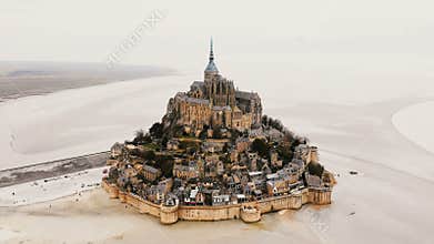 Drone zooming in on Mont Saint Michel abbey, epic island fortress town and famous travel landmark in Normandy France.
