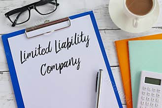 Top view of glasses,coffee,books,calculator,pen,clipboard and paper written with Limited Liability Company