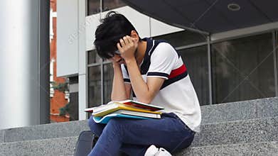 Asian student man sitting on stairs and reading books