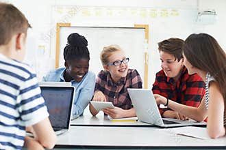 Group Of Teenage Students Collaborating On Project In IT Class