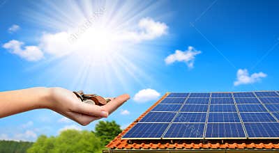 Solar panel on the roof of the house and coins in hand.