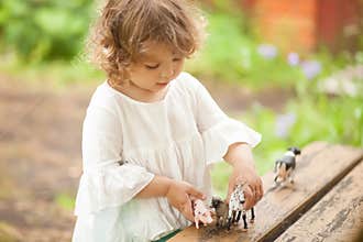 Adorable little girl play with animal toys.