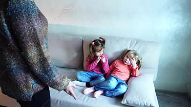 Two girls sit on couch and listen to mom`s remarks about bad behavior.