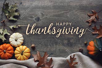 Happy Thanksgiving typography with pumpkins and leaves over dark wood background