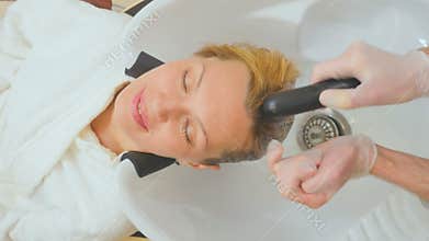 Man beautician washes hair of client in beauty clinic