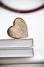 Wooden heart shape on a open book. Love reading concept close up.