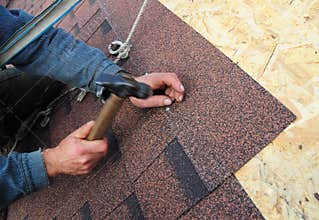 Roofer Install Asphalt Roof Shingles. Close up view on Roofer Installation Asphalt Roofing Shingles Installation.