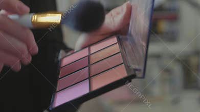 A palette with eye shadows and a makeup brush: women`s cosmetics.