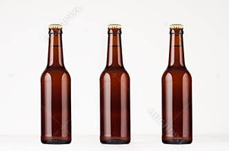 Three brown longneck beer bottle 330ml mock up. Template on white wood table.