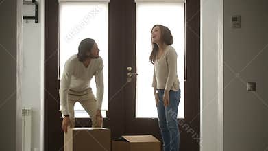 Happy family couple holding boxes opening door entering new house