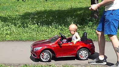 Baby boy is riding a toy car driven by father