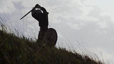 Silhouettes of two warriors Viking are fighting with swords and shields.