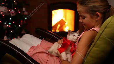 Young girl holding her christmas present by the fire - caressing a rescue adopted kitten