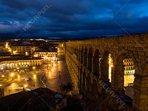 Segovia, Spain at the ancient Roman aqueduct. The Aqueduct of Segovia, located in Plaza del Azoguejo, is the defining historical f