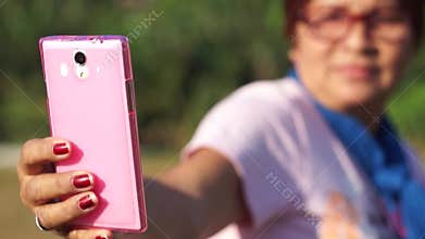 Mature woman self portraits herself with the use of mobile smartphone