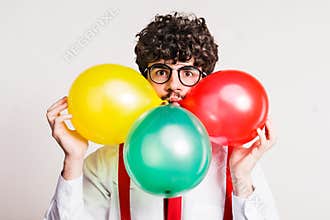 Portrait of a young man with balloons in a studio.