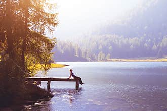 Happy woman sitting on the pier and smiling, happiness or inspiration concept