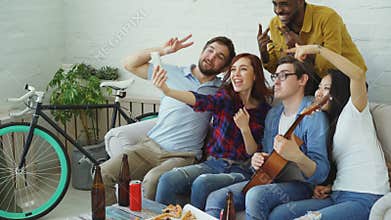 Happy student friends taking selfie on smartphone camera and posing while have home party in shared accommodation