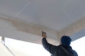 Skilled worker spreads stucco and paint on a beam of a terrace d