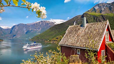 Red cottage against cruise ship in fjord, Flam, Norway