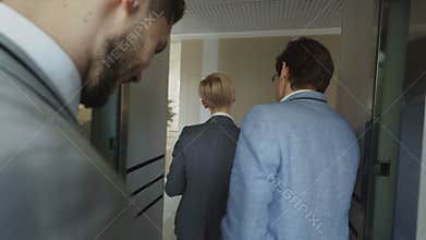 Tracking shot of Businesswomen and businessmen colleagues talking in moving elevator and come out from it and walking in