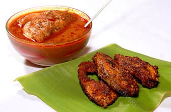 Meen kulambu with fish fry on a leaf.