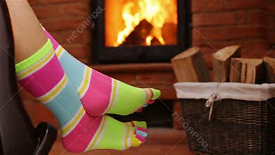 Woman feet hanging on rocking chair, swinging in front of fireplace