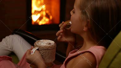 Young girl drinks hot chocolate and eats heart shaped cookie