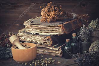 Tincture bottles, bunches of healthy herbs, stack of antique books, mortars, sack of medicinal herbs. Herbal medicine.