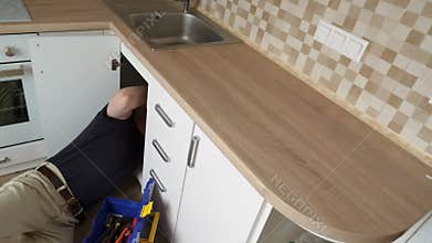 Working plumber at the kitchen.