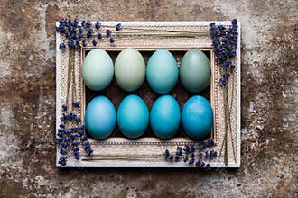 Happy Easter rustic background with copy space. DIY dyed various shades of blue Easter eggs and vintage wooden picture frame.