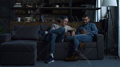 Hipster best friends with smartphones on the couch