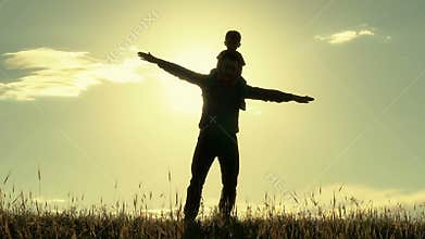 Silhouette of father and son on sunset background. Dad and son show the flight themselves