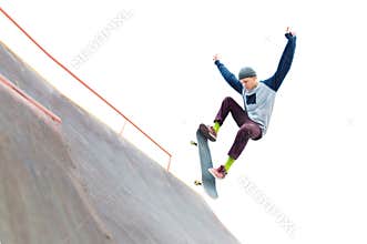 The teenager skateboarder in the cap does a trick with a jump on the ramp in the skatepark. Isolated skater and ramp on
