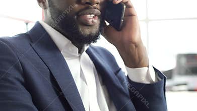 Pleased African-American man in suit talking on cellphone, making an appointment