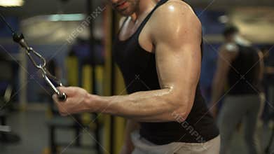 Guy working hard in gym doing brisk pull-downs with one arm, finishing exercise