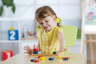 Little child girl plays in kindergarten in Montessori preschool class.