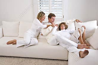 Family relaxing at home on white living room sofa