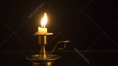 Burning candle on the old brass candlestick