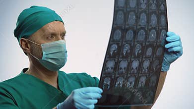 Male physician checking brain scan, treatment results, patient getting better