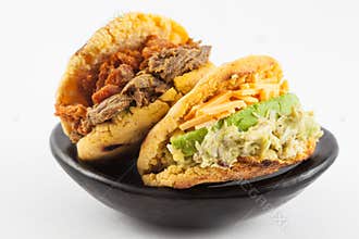 Arepas filled with shredded beef and pork rind served in a black ceramic dish
