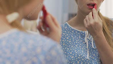 Shy girl applying red lipstick, nerd overcoming insecurities, self-confidence