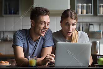 Surprised couple amazed with online shopping sale looking at lap
